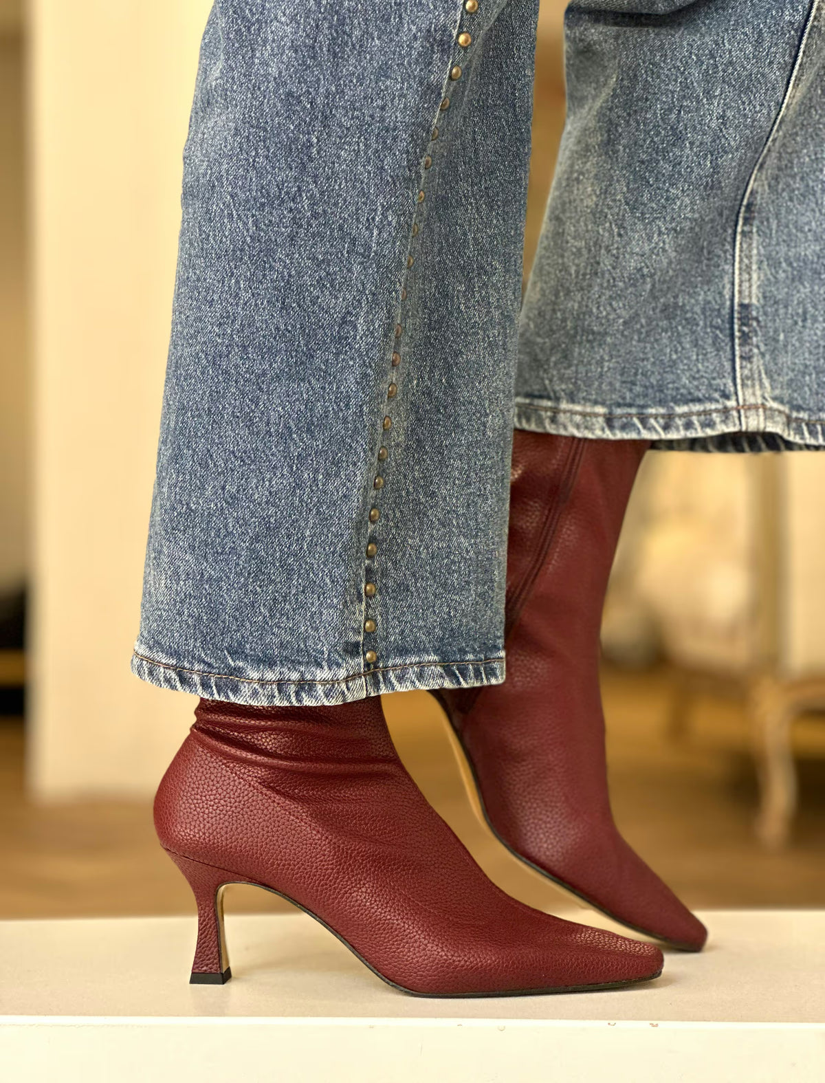 Botines burdeos Poppy de punta afilada y tacón fino combinados con vaqueros anchos.