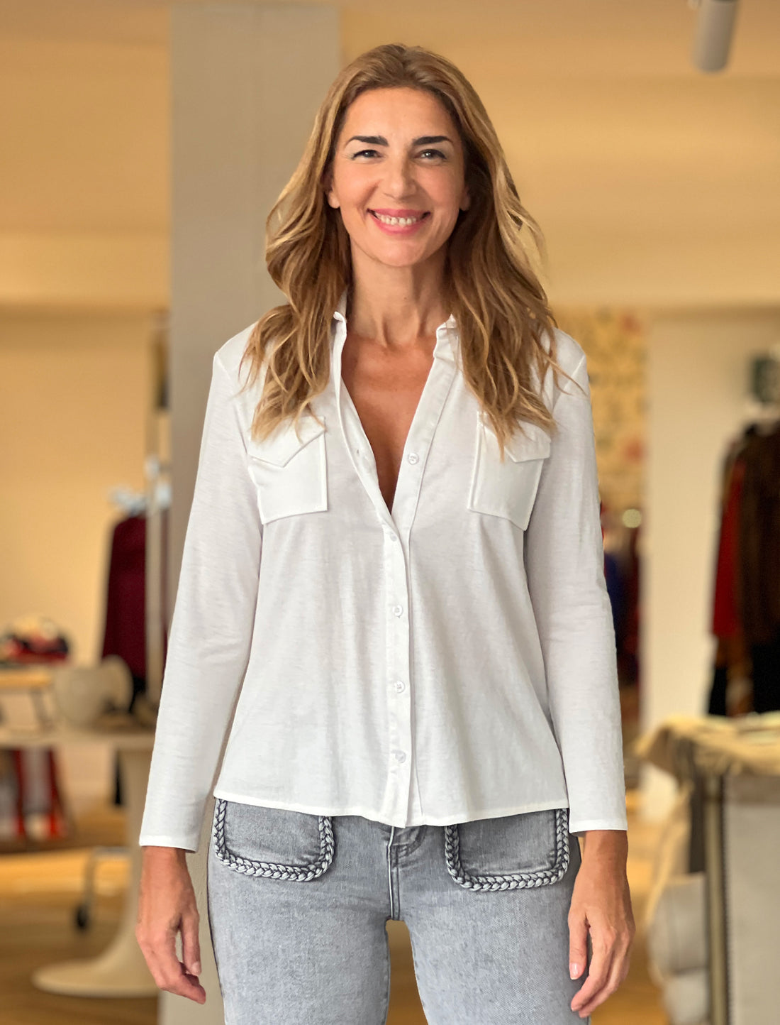 Camisa blanca elegante para mujer con cuello pico y bolsillos delanteros.