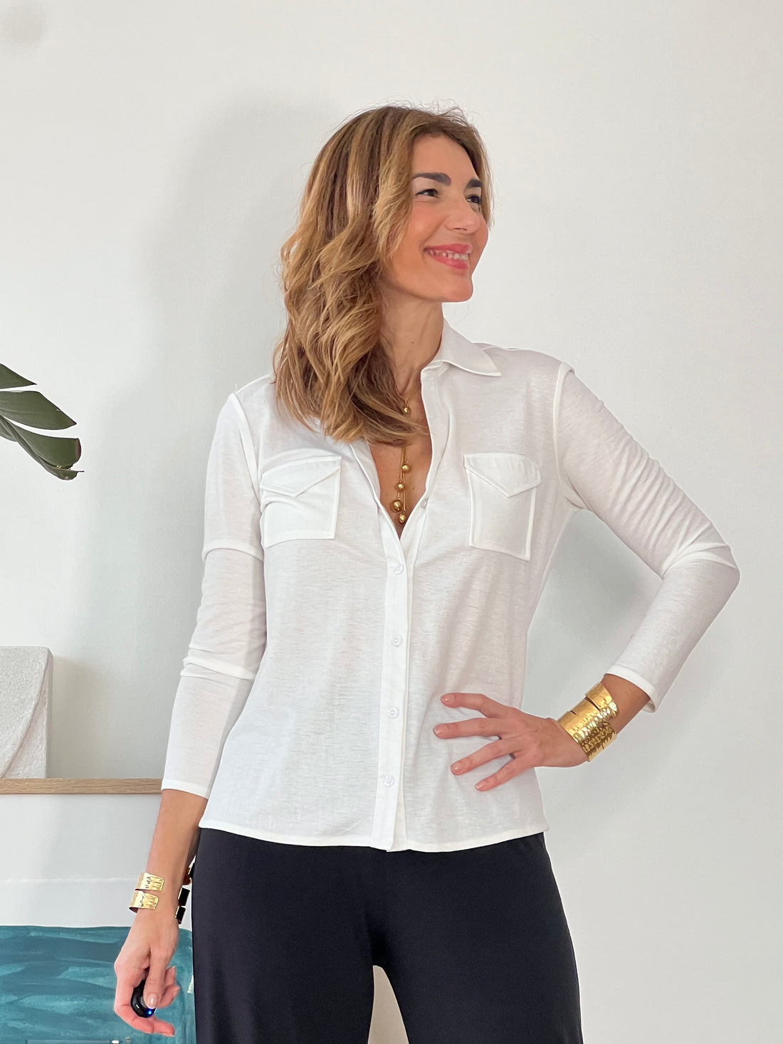 Camisa blanca elegante para mujer con cuello pico y bolsillos delanteros.