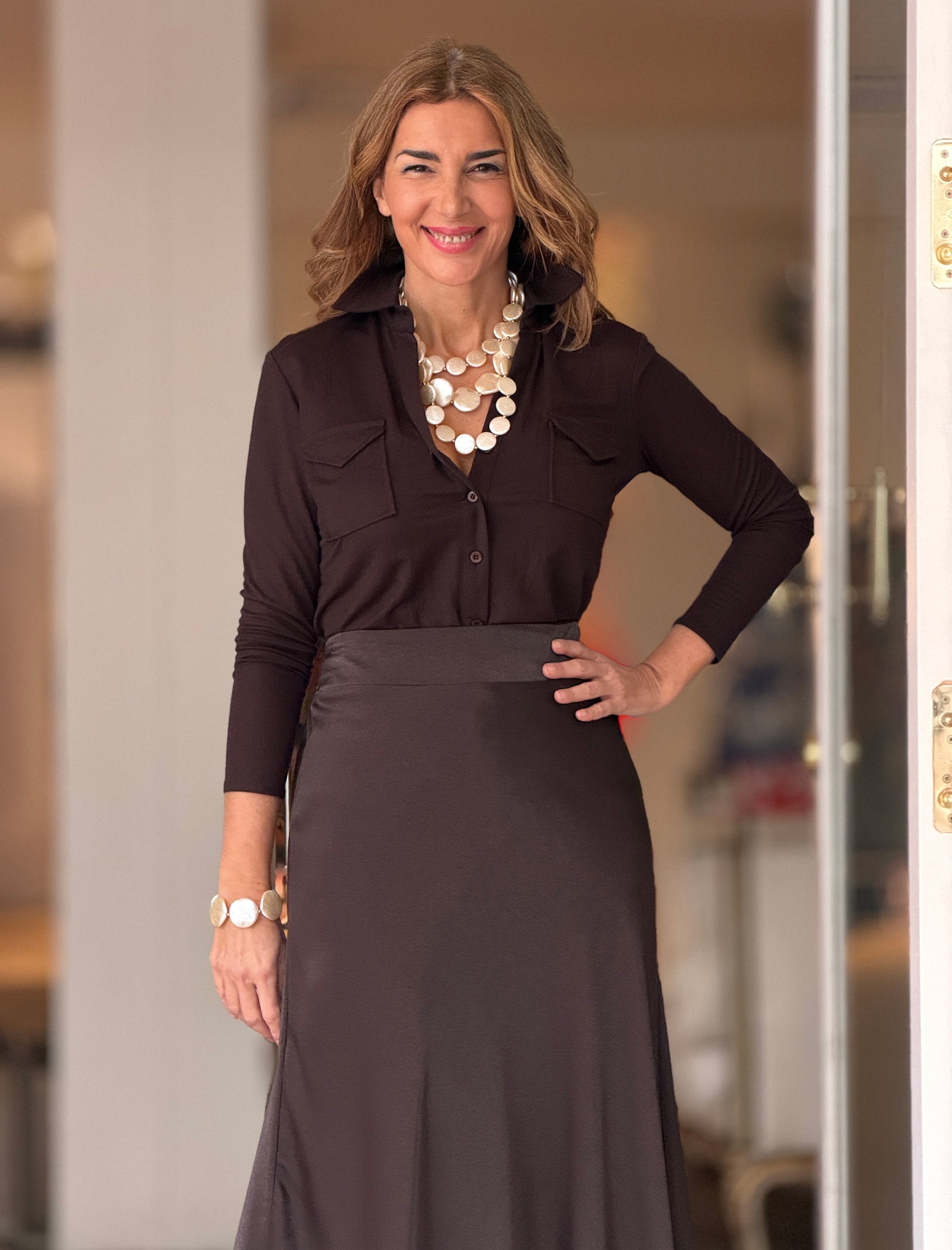 Outfit de oficina con camisa marrón para mujer y falda beige de estilo elegante.