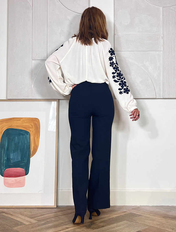 Vista trasera de pantalón azul marino para mujer con corte recto y caída fluida.