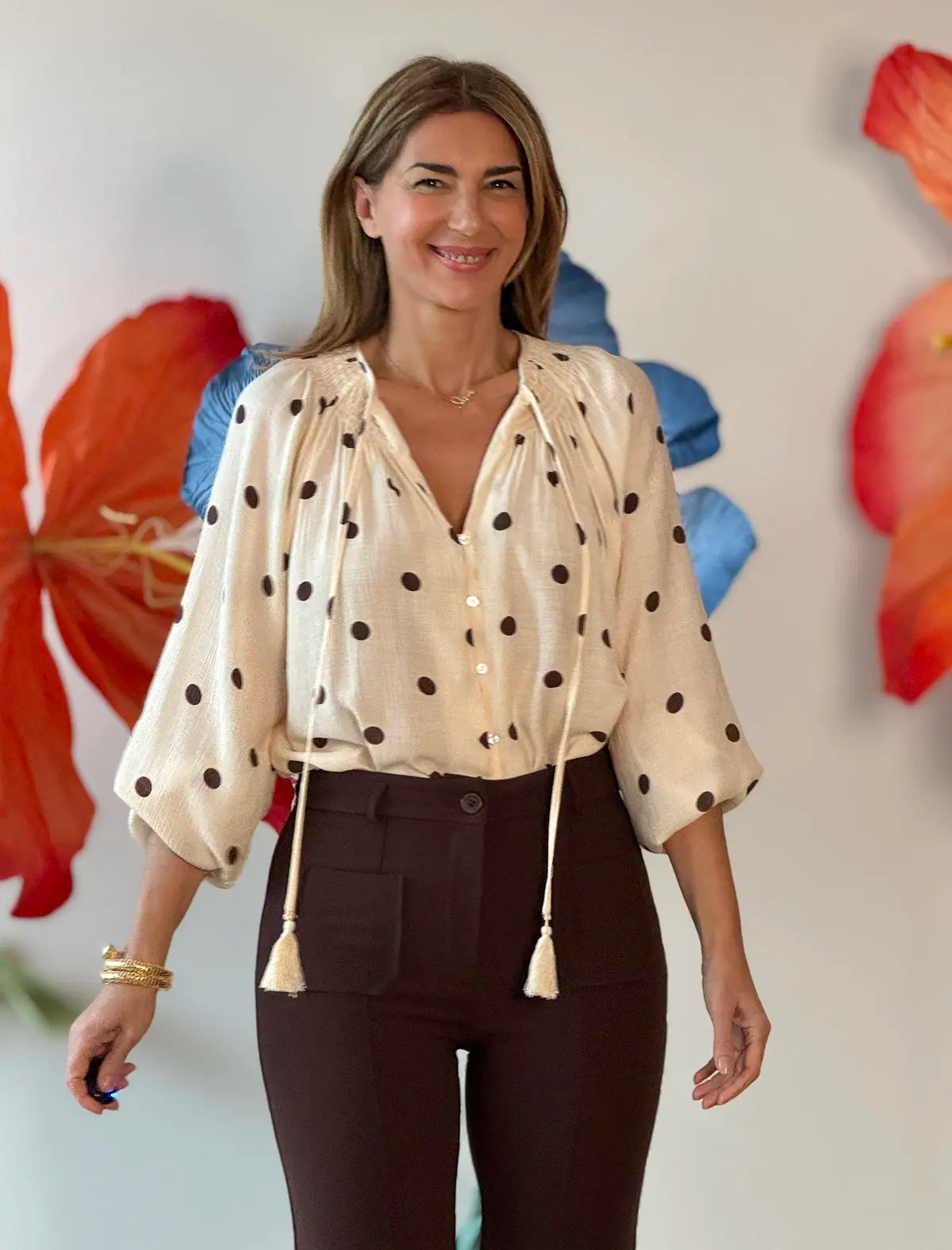 Pantalón marrón para mujer combinado con blusa estampada en un look femenino.