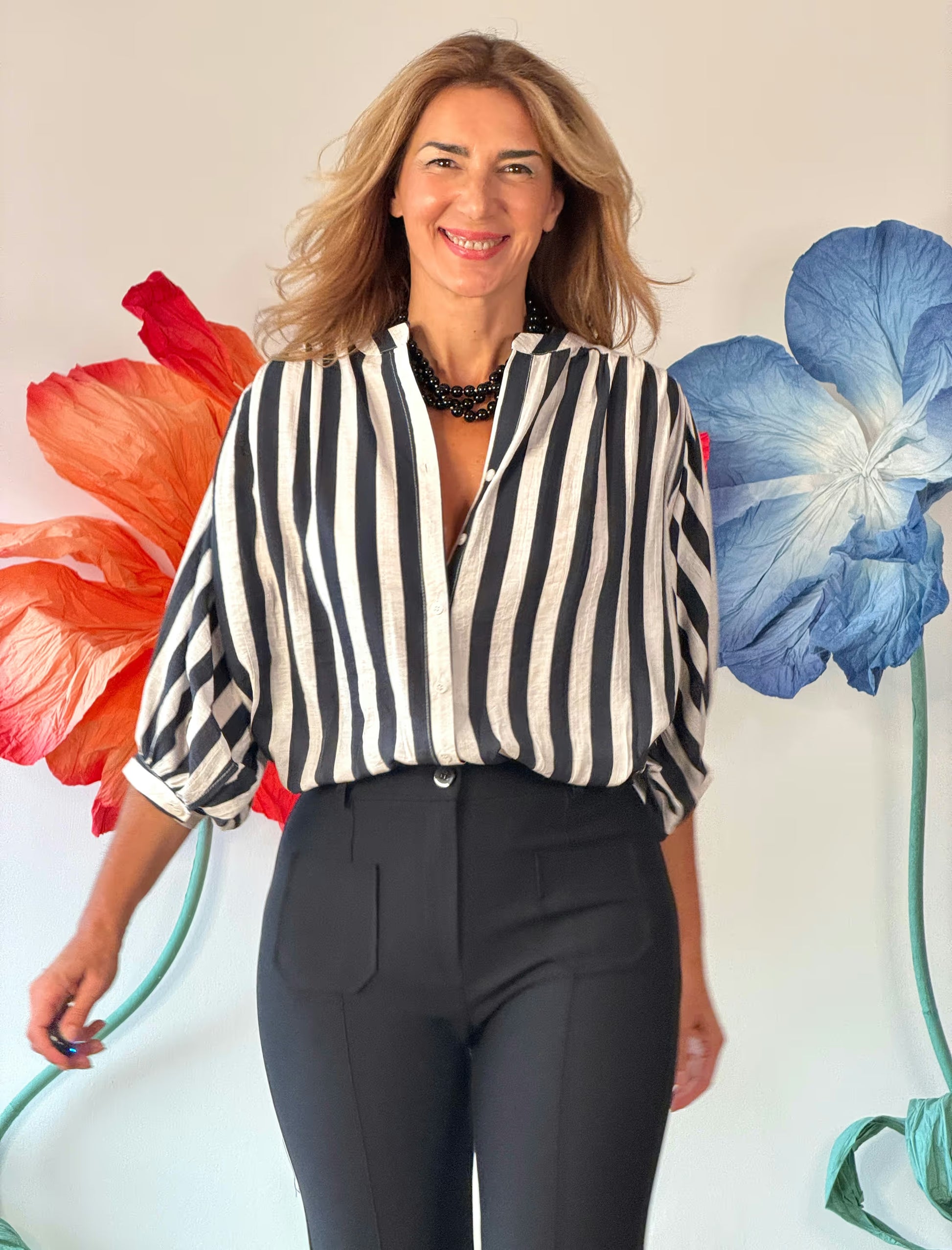 Look formal de mujer con pantalón negro recto y camisa de vestir de rayas.