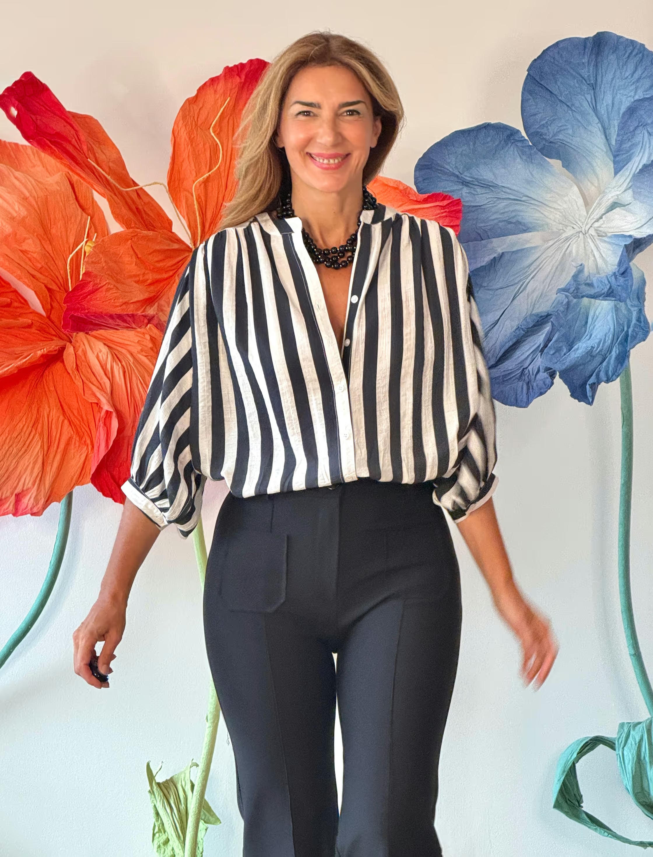 Pantalón negro elegante para mujer combinado con camisa de rayas en un look moderno.