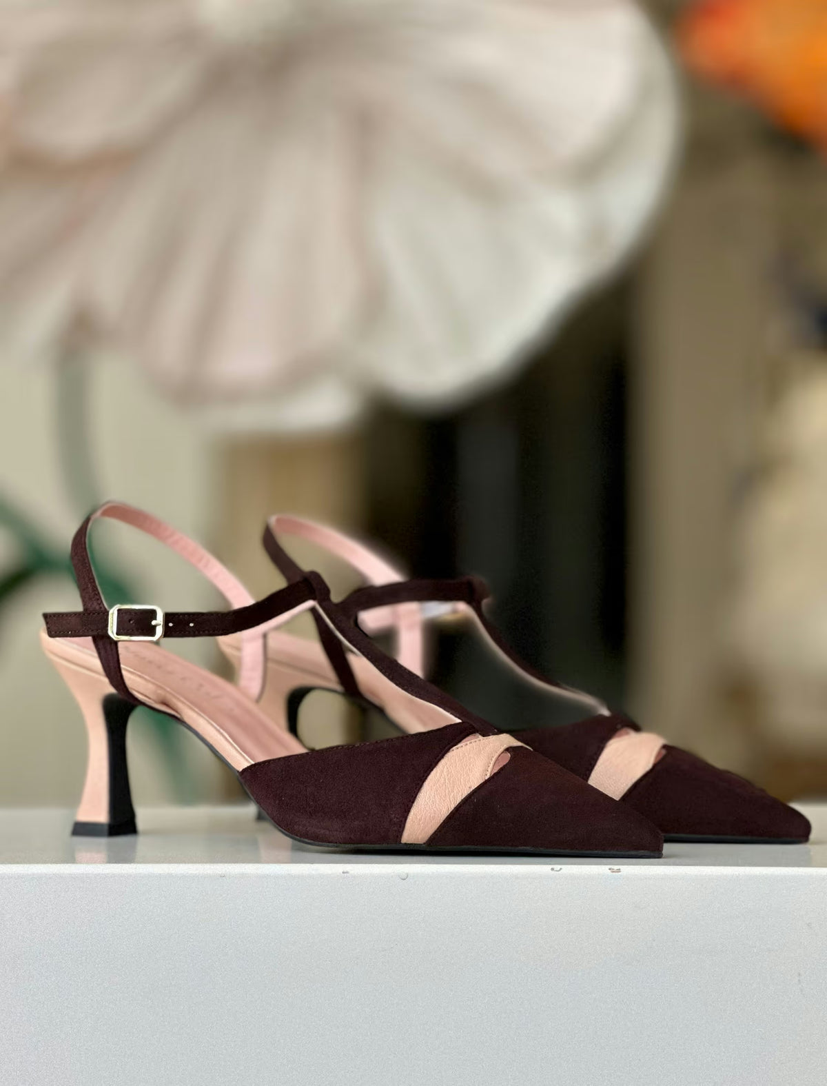 Par de zapatos de salón nude y marrón  sobre superficie blanca